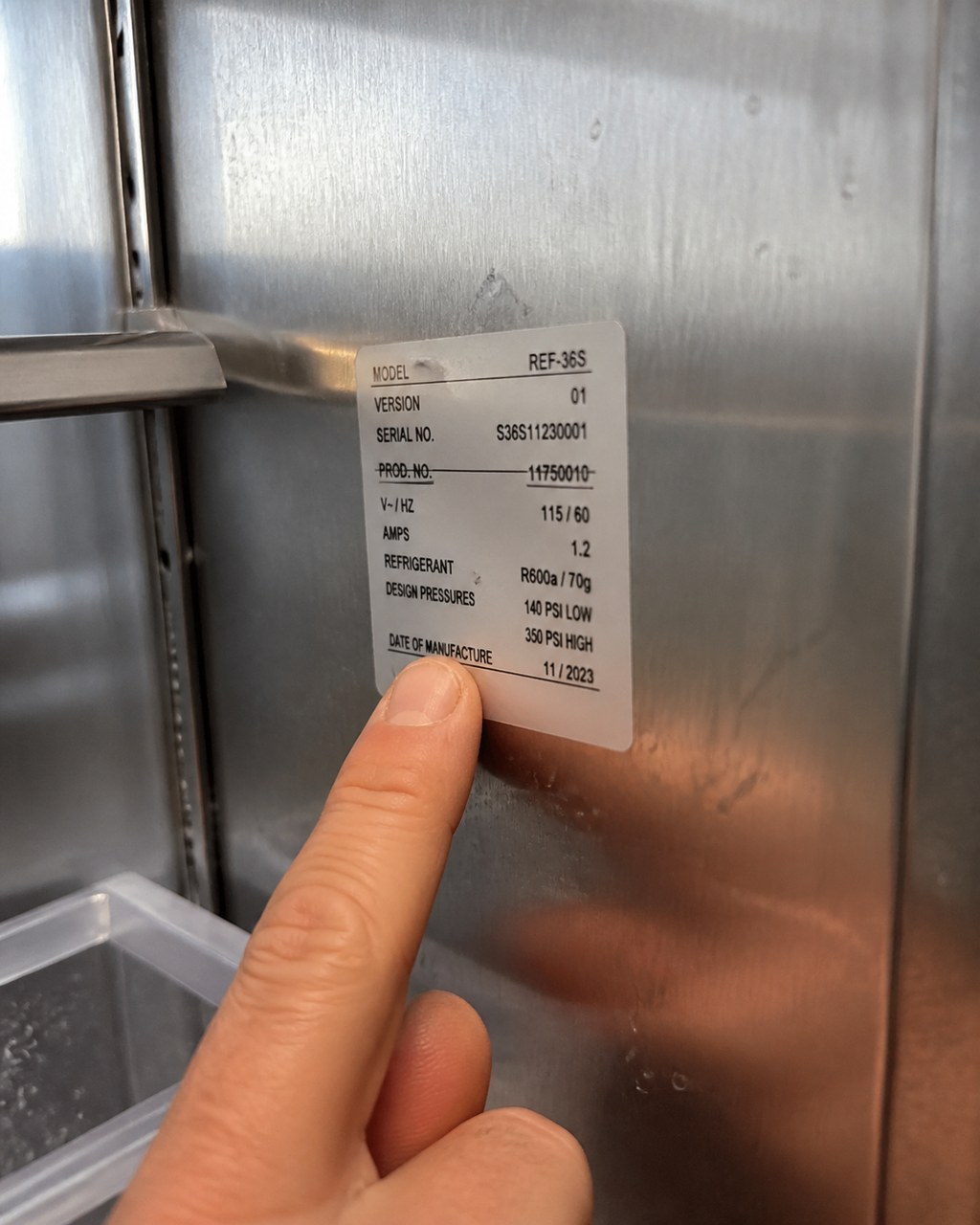 Technician pointing to the model and serial sticker inside a Sub-Zero cabinet